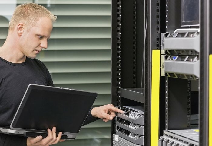 It consultant working with servers It engineer or consultant standing with a laptop and monitor blade servers in data rack. Shot in datacenter.