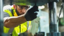 Close up hand industrial industrial plant with a tablet in hand, Engineer looking of working at industrial machinery setup in factory.